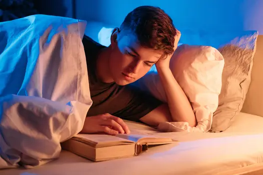 photo of man reading book late at night