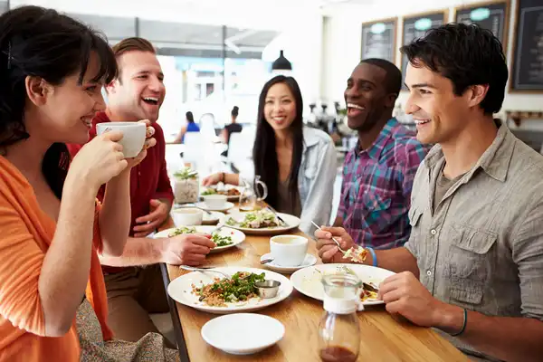 photo of adult friends eating meal in restaurant