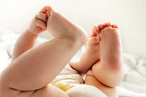photo of baby playing with feet