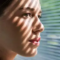 photo of young woman looking through blinds