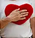 male right hand holding heartshaped red cushion 