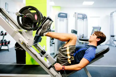 photo of young man using leg press in gym