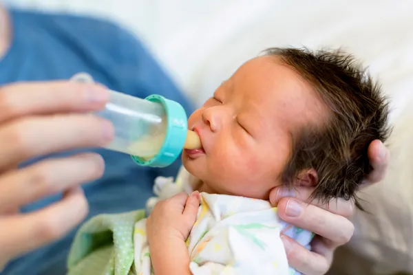photo of newborn drinking milk from bottle