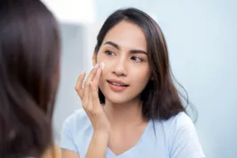 photo of woman applying face lotion