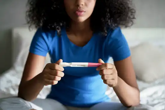 photo of woman holding pregnancy test