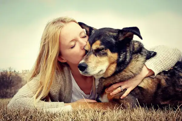 photo of woman kissing dog