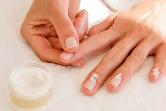 photo of woman moisturizing fingernails