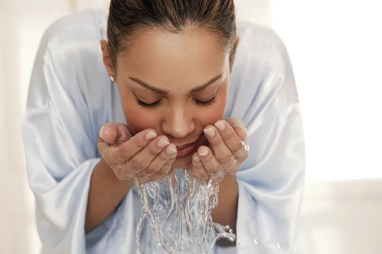 photo of woman splashing water on face