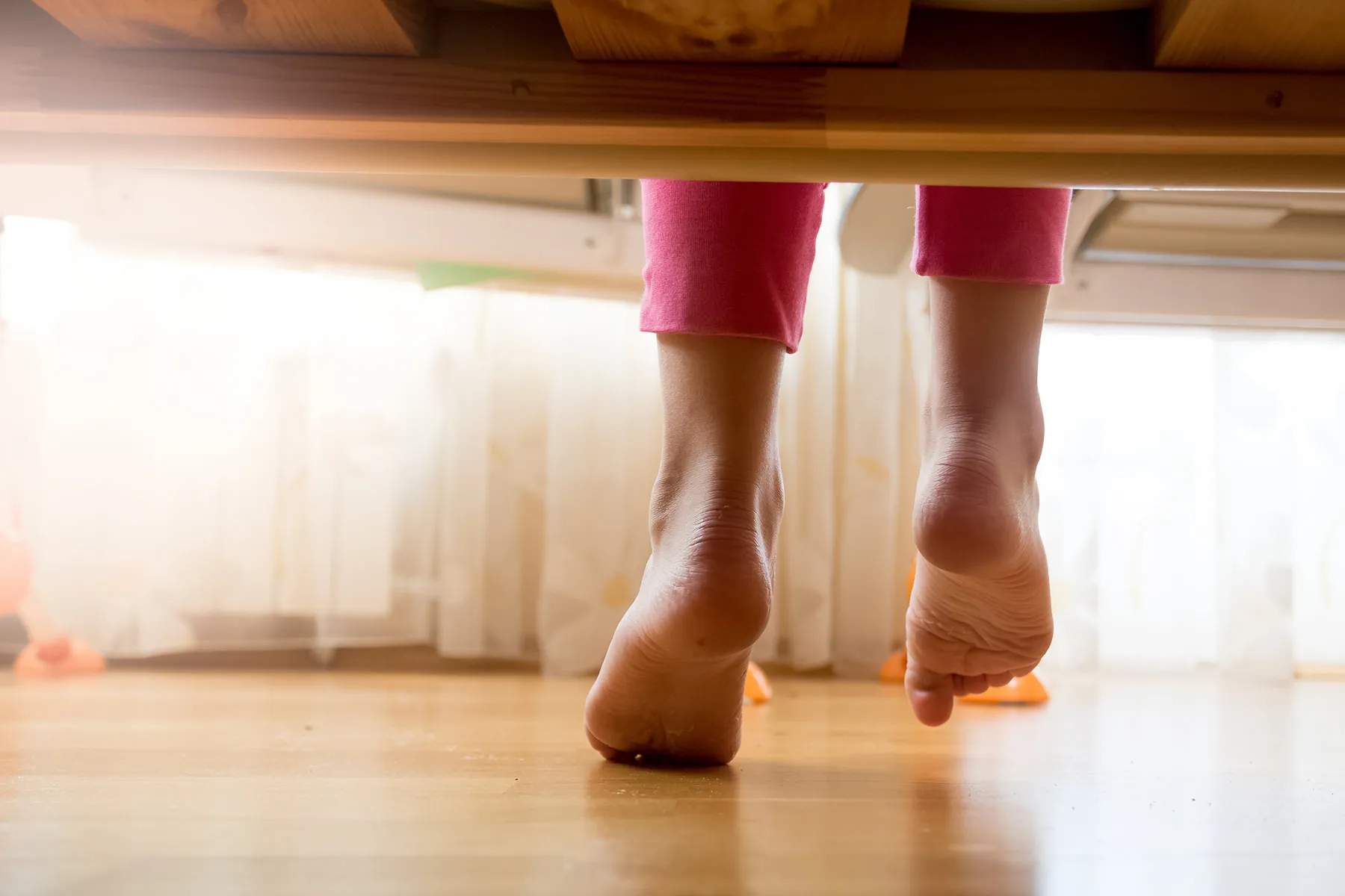 photo of woman stepping from bed onto floor