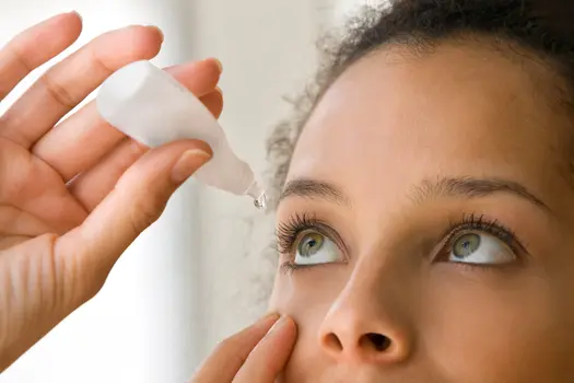photo of woman using eye drops