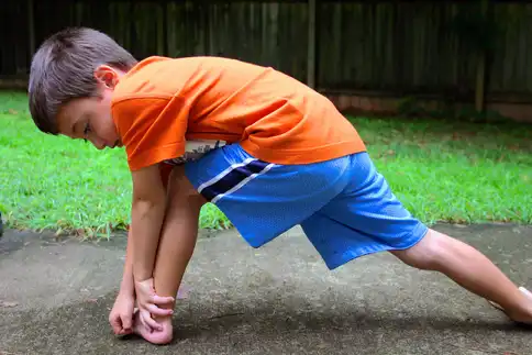 photo of young boy stretching outdoors