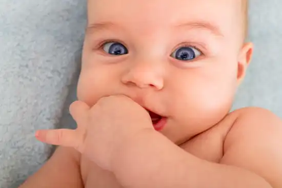 photo of baby with hand in its mouth