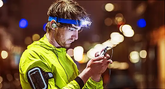 Runner looking on smartphone, wearing head torch