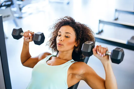 photo of woman lifting hand weights in gym