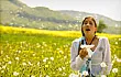Woman sneezing with tissue in meadow