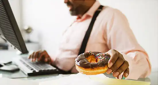 man eating doughnut in office