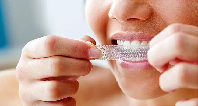 woman using teeth whitening strip
