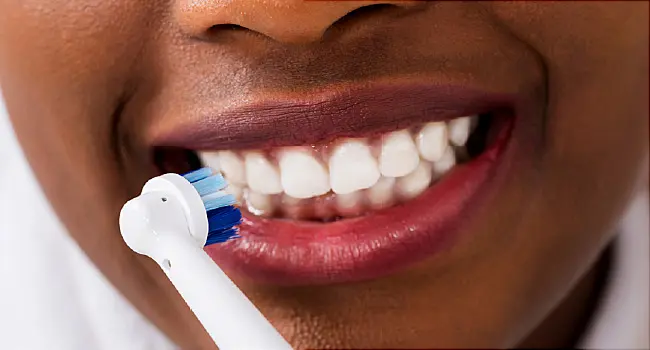 woman brushing her teeth with electric toothbrush