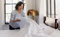 photo of mature woman making bed