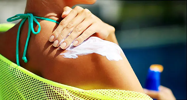 woman applying sunscreen to shoulder close up