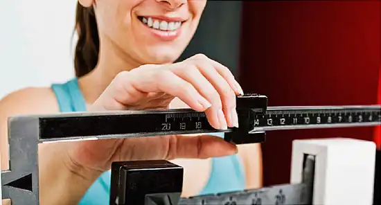 woman checking her weight on scale