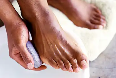 man rubbing feet with pumice stone