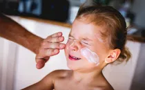 applying sunscreen on boys face