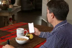 photo of man eating breakfast & using smartphone