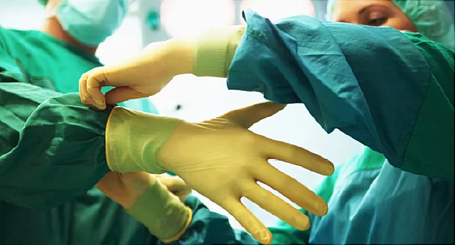 nurse helps doctor put on gloves