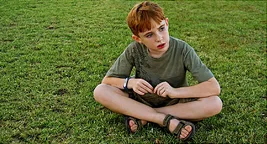 sad kid sitting in grass