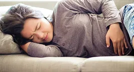 girl with stomach pain lying on couch
