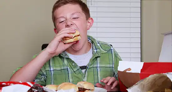 young boy eating a hamburger