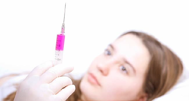 syringe in foreground young girl in background