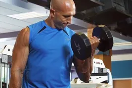 photo of man doing curls in gym