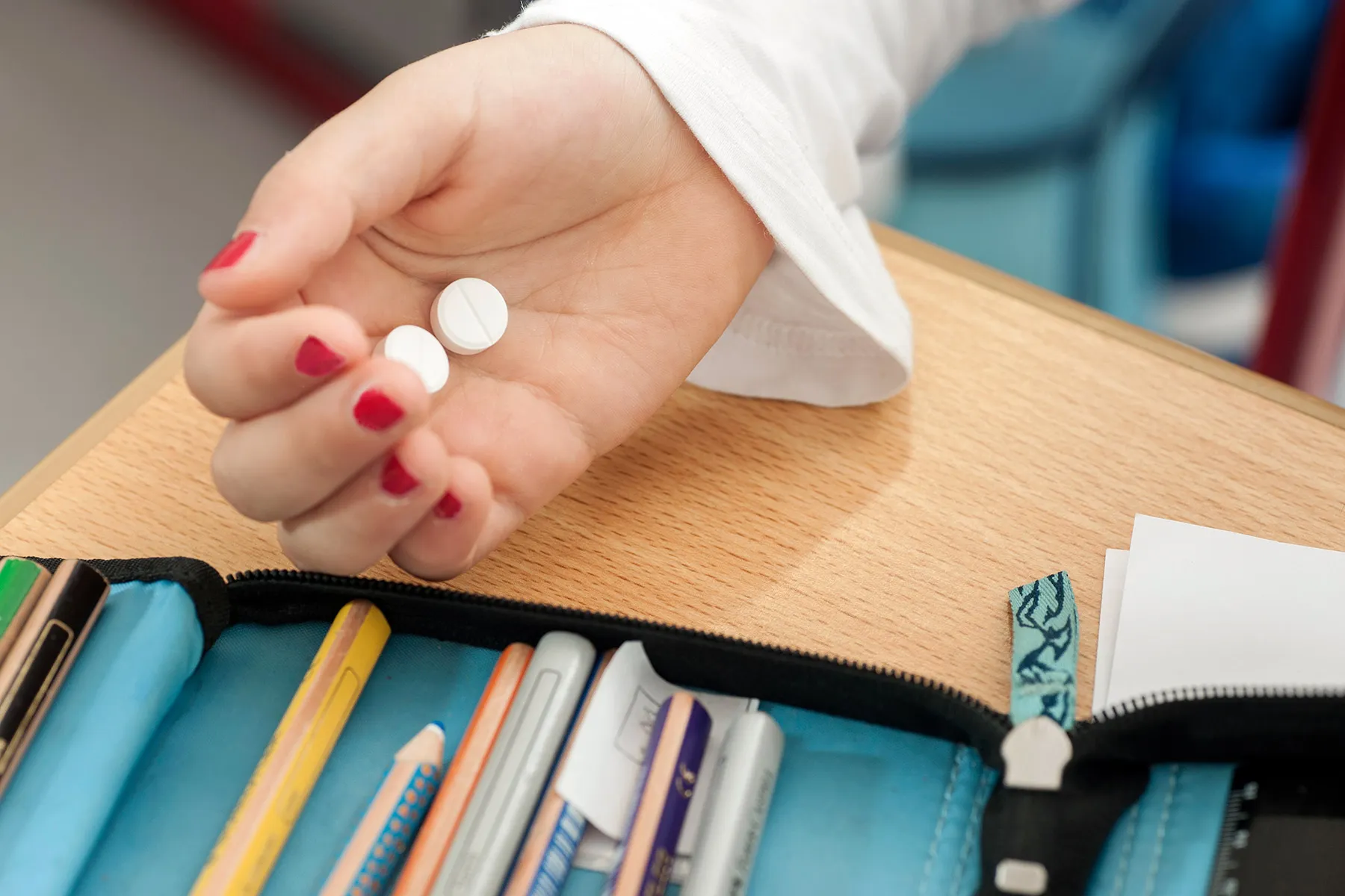 photo of child in school holding pills in hand