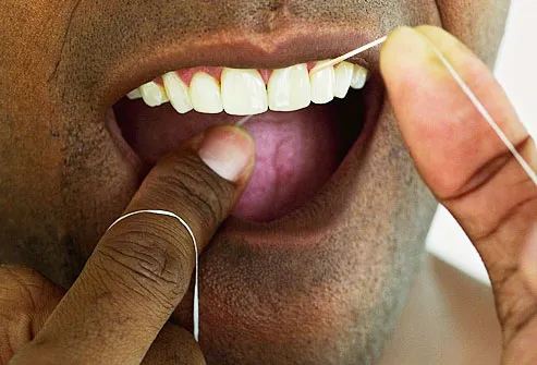 man cleaning his teeth with dental floss