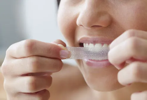 young woman using a teeth whitening strip