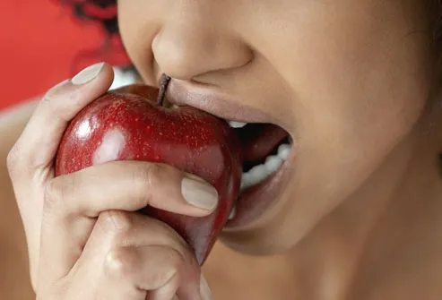 Woman biting into a red apple