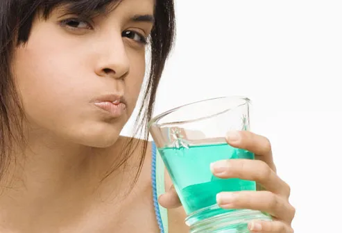 Young woman gargling with blue mouthwash