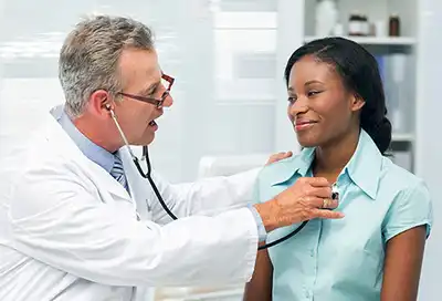 doctor listening to womans chest with stethoscope