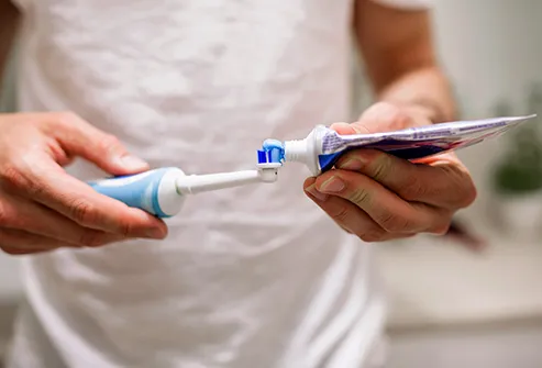 person squeezing toothpaste