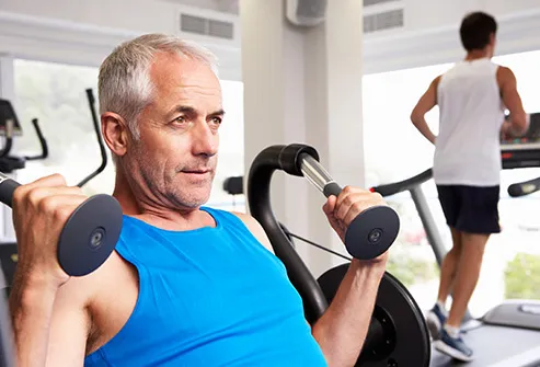 senior man lifting weights in gym