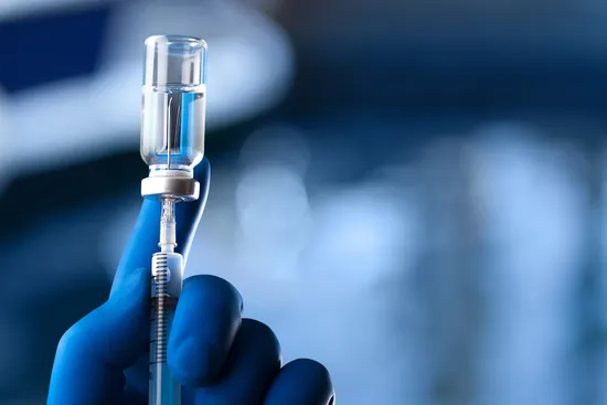 photo of hand in glove holds ampoule with vaccine