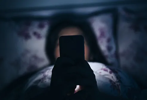 woman using cell phone in bed