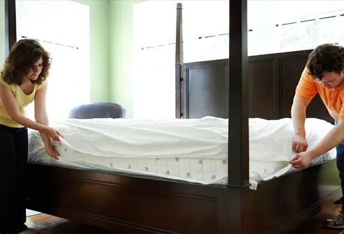 Couple putting allergen-proof cover on mattress