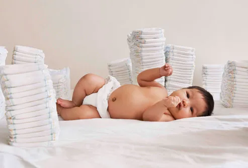 Baby lying on side with stacks of diapers