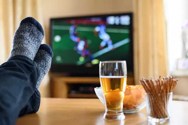 photo of man watching sports with beer and snacks