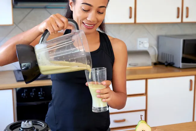 photo of woman pouring green smoothie