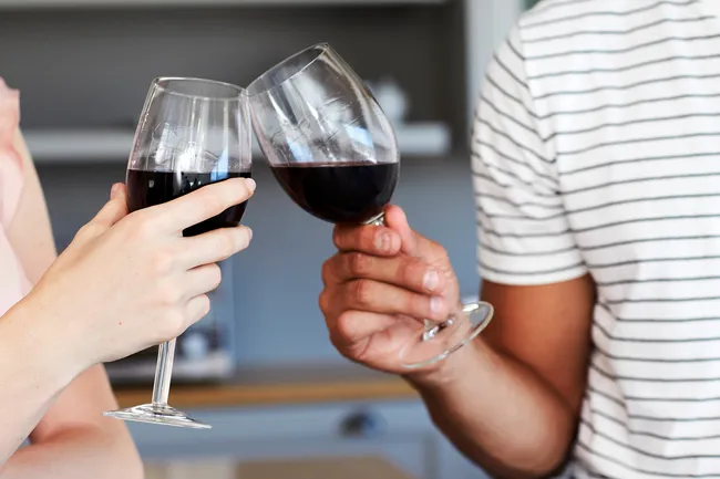 photo of man and woman toasting glasses red wine
