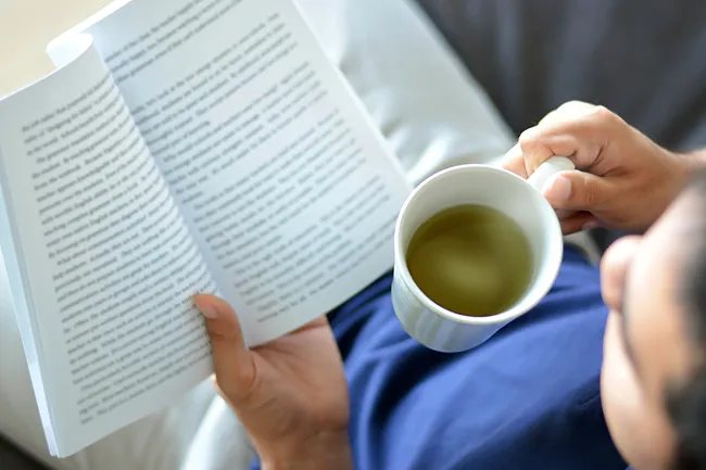 man reading book and drinking tea
